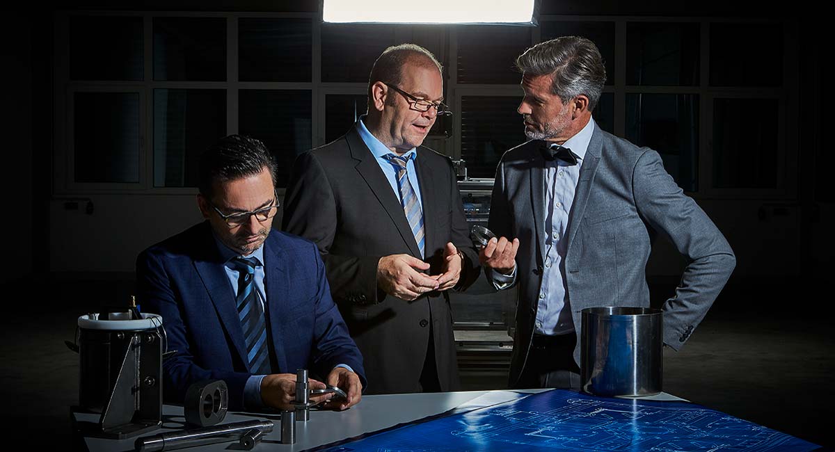 3 Herren am Tisch mit technischen Einzelteilen des Vision Q