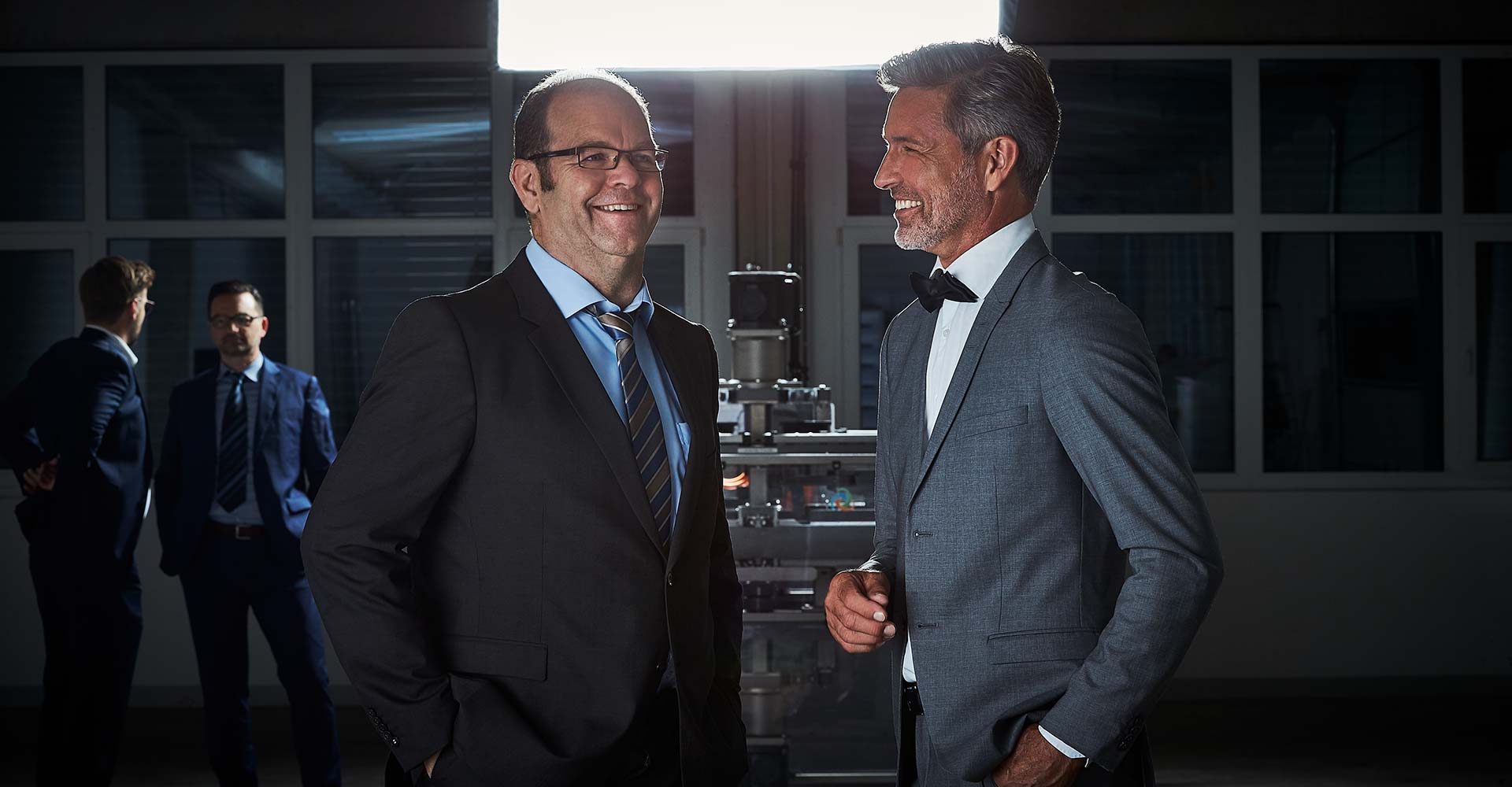 2 Herren im Anzug vor dem Vision Q, 2 Herren im Anzug stehen im Hintergrund